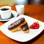 Plate of two chocolate èclairs and a strawberry