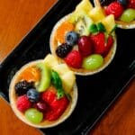 Three assorted fresh fruit tarts on a tray