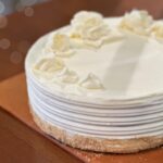 Freshly made white cheesecake with floral piping on top and a graham cracker rim